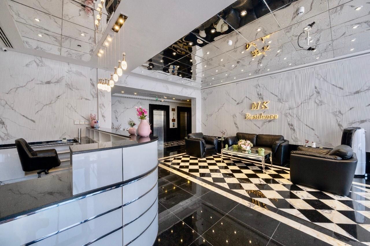 MK Residence lobby with marble walls, a mirrored ceiling, the gold MK Residence sign and a black and white tiled floor